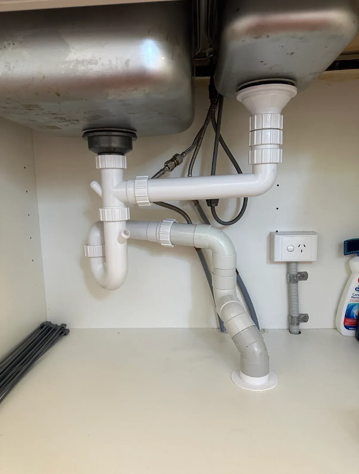 Waste trap and pipe connections beneath a double kitchen sink