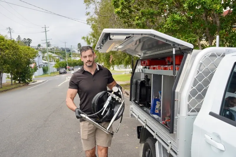 Supplied photo of a plumber with drain equipment beside a work ute
