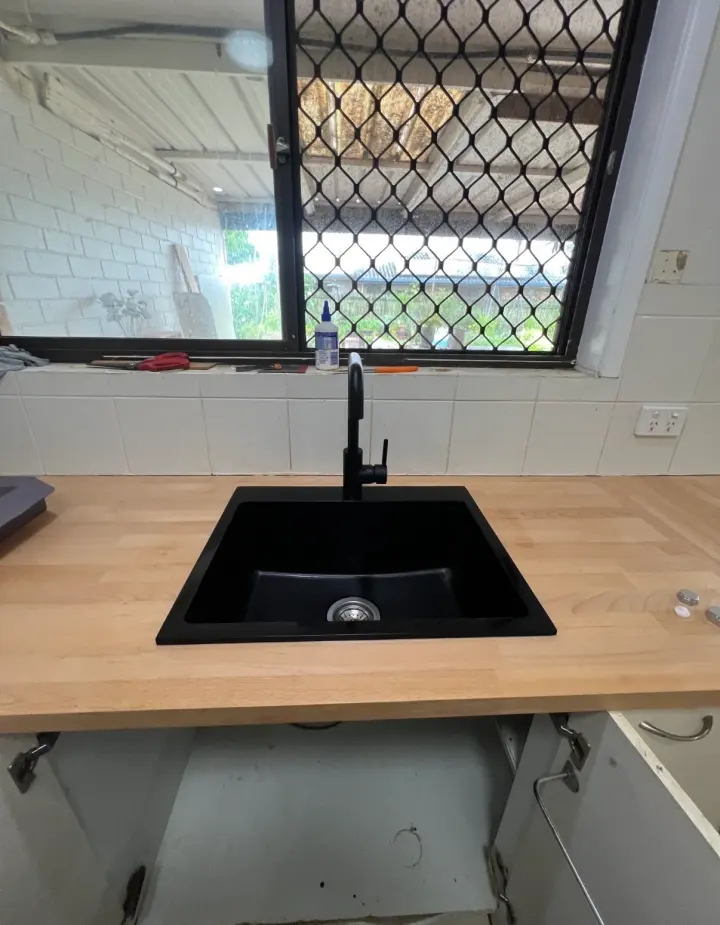 Black kitchen sink and mixer set into a timber benchtop