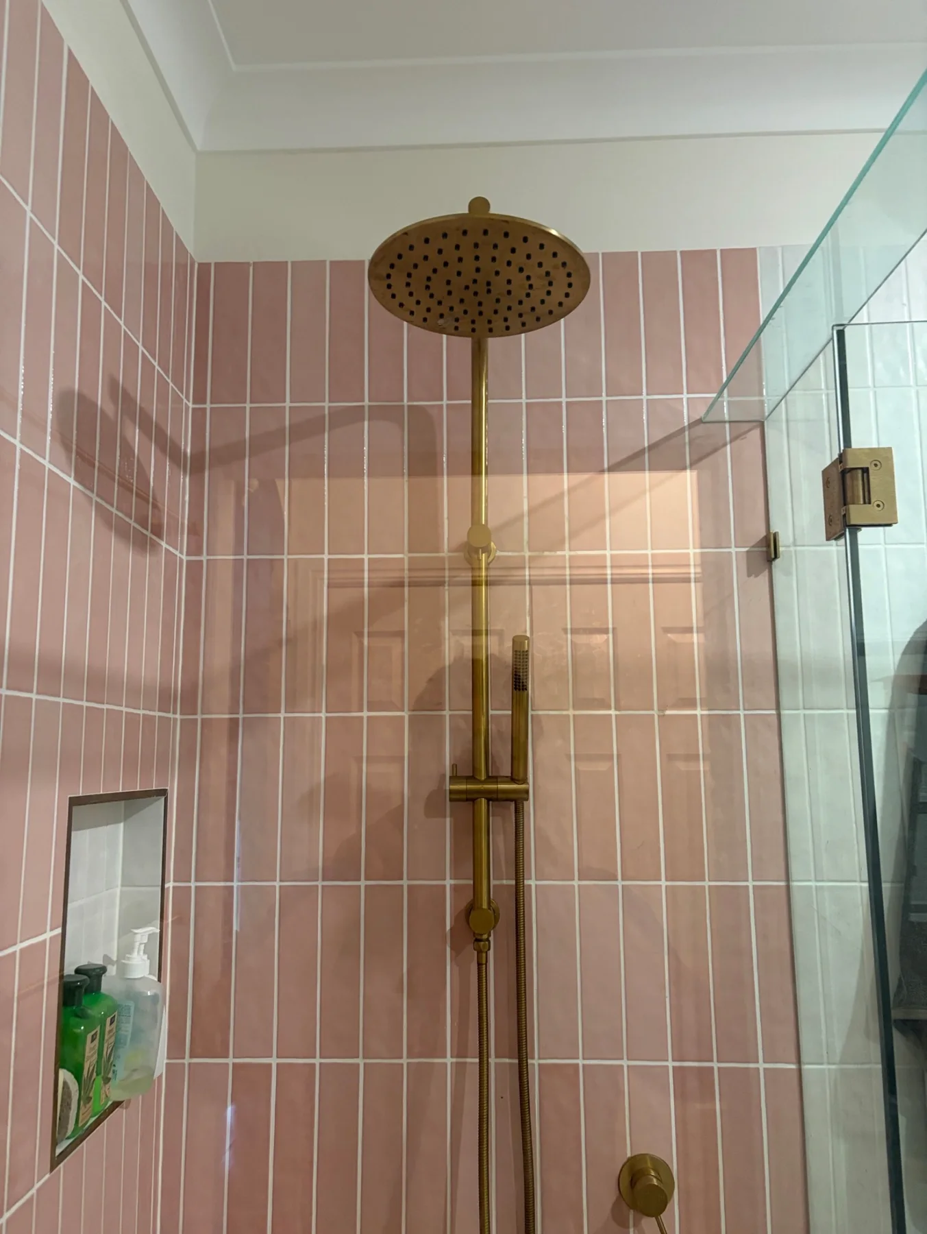 Brass shower fittings, pink tiles and a glass shower screen